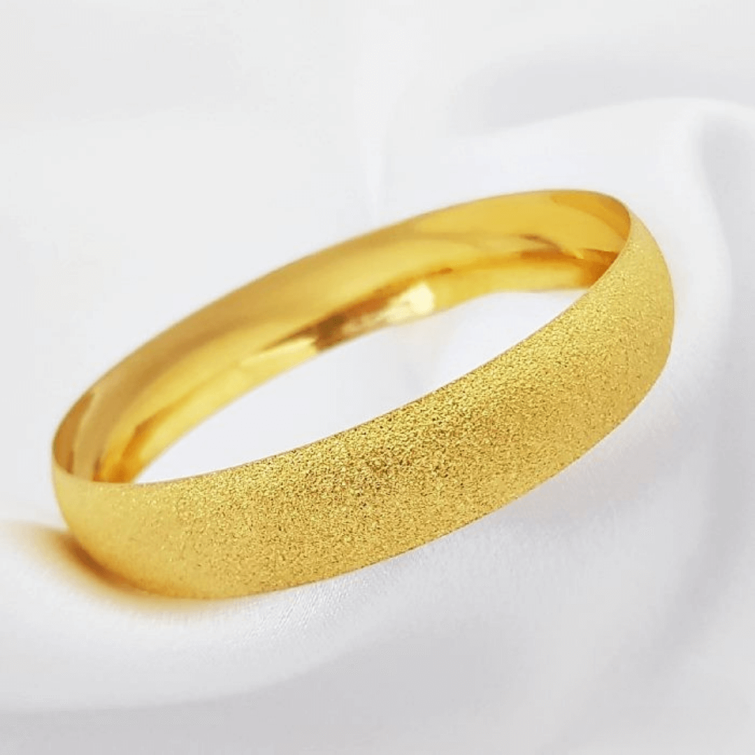 GOLD BANGLE featuring a smooth and textured design on a soft white background.
